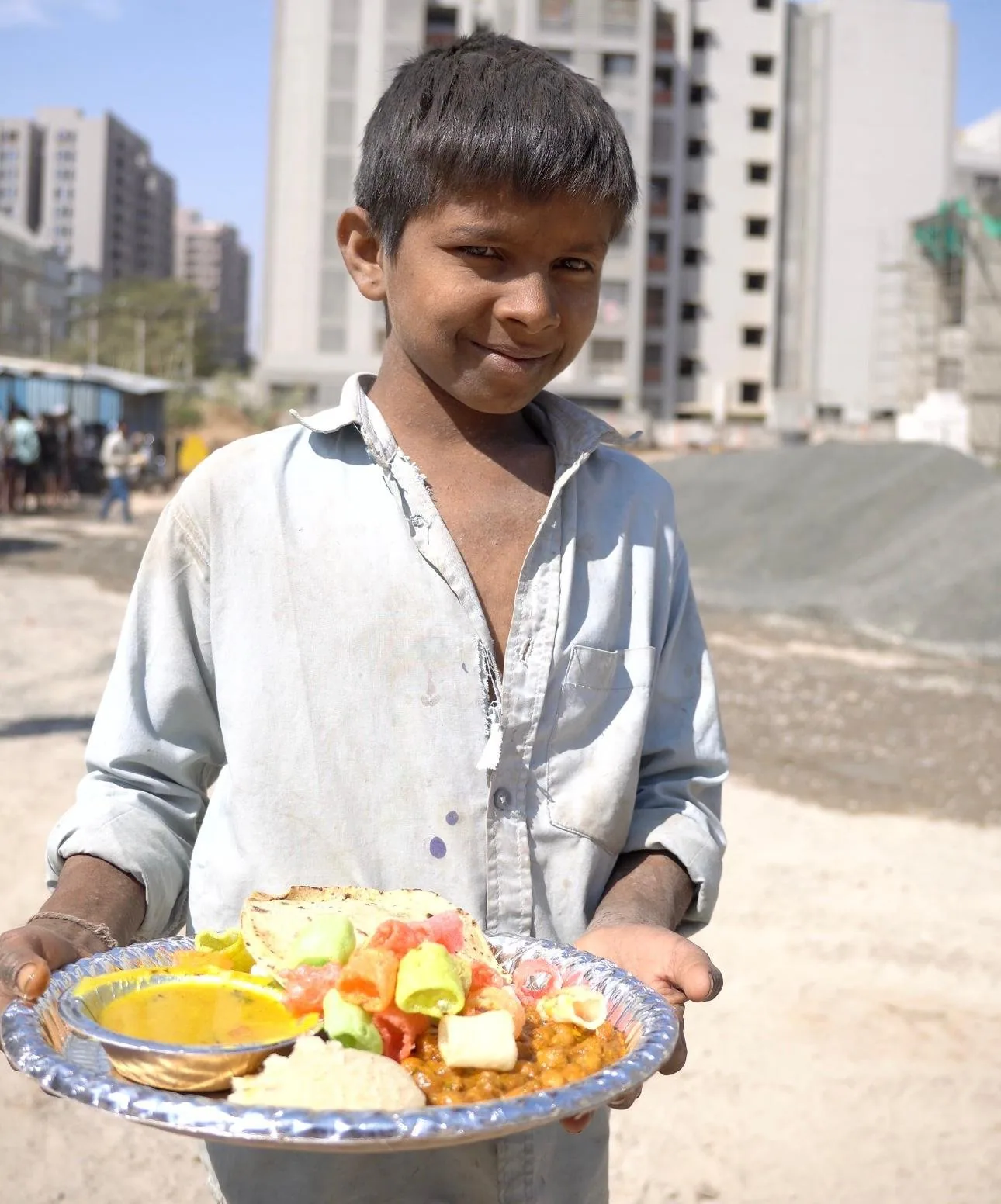 A boy holding a plate of chana, roti and paneer received from Shree Foundation volunteers