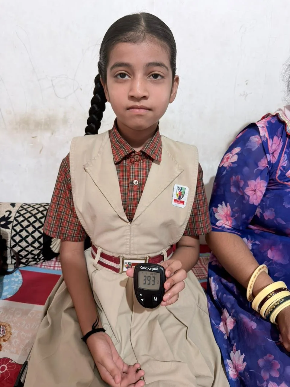 A schoolgirl in uniform showing her blood glucose reading during a Type 1 diabetes check-up