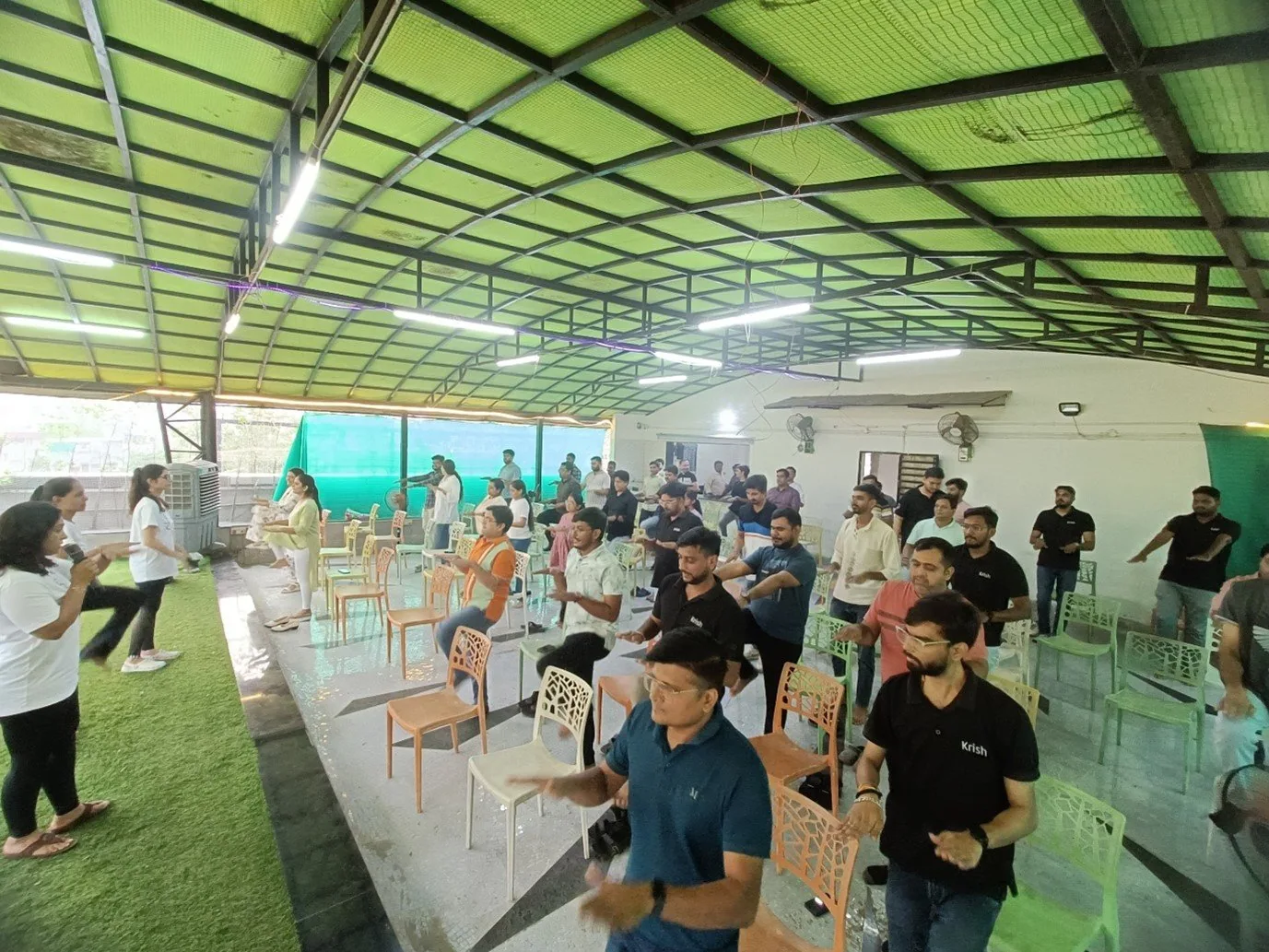 A large group taking part in a Shree Foundation corporate wellness session under a covered pavilion