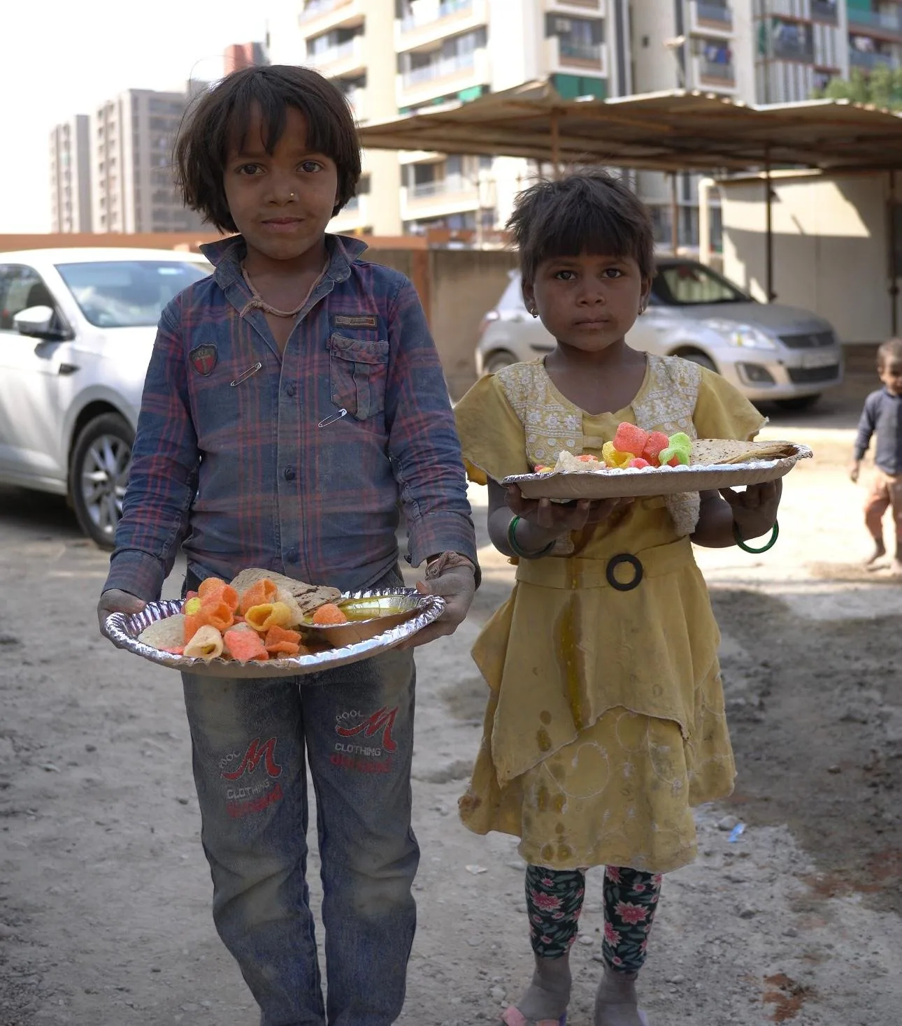 Two children holding plates of food received at a Shree Foundation meal drive